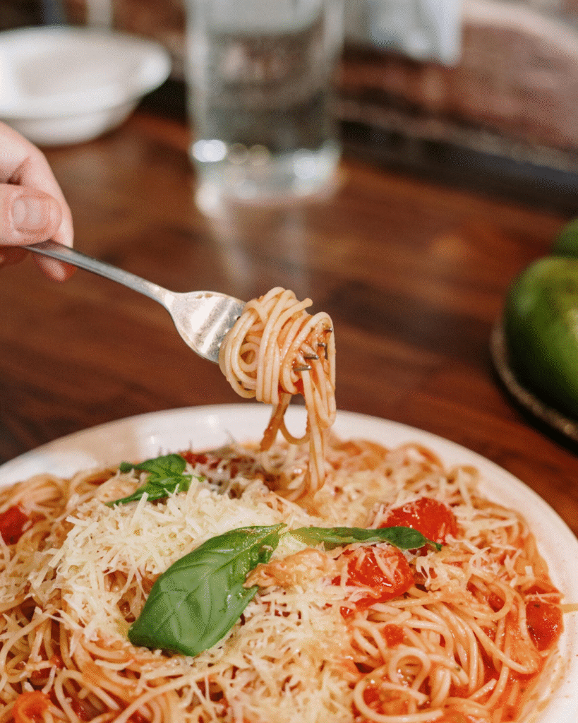 A delicious spread of famous Italian cuisine including wood-fired pizza, creamy pasta, and fresh bruschetta on a rustic table.