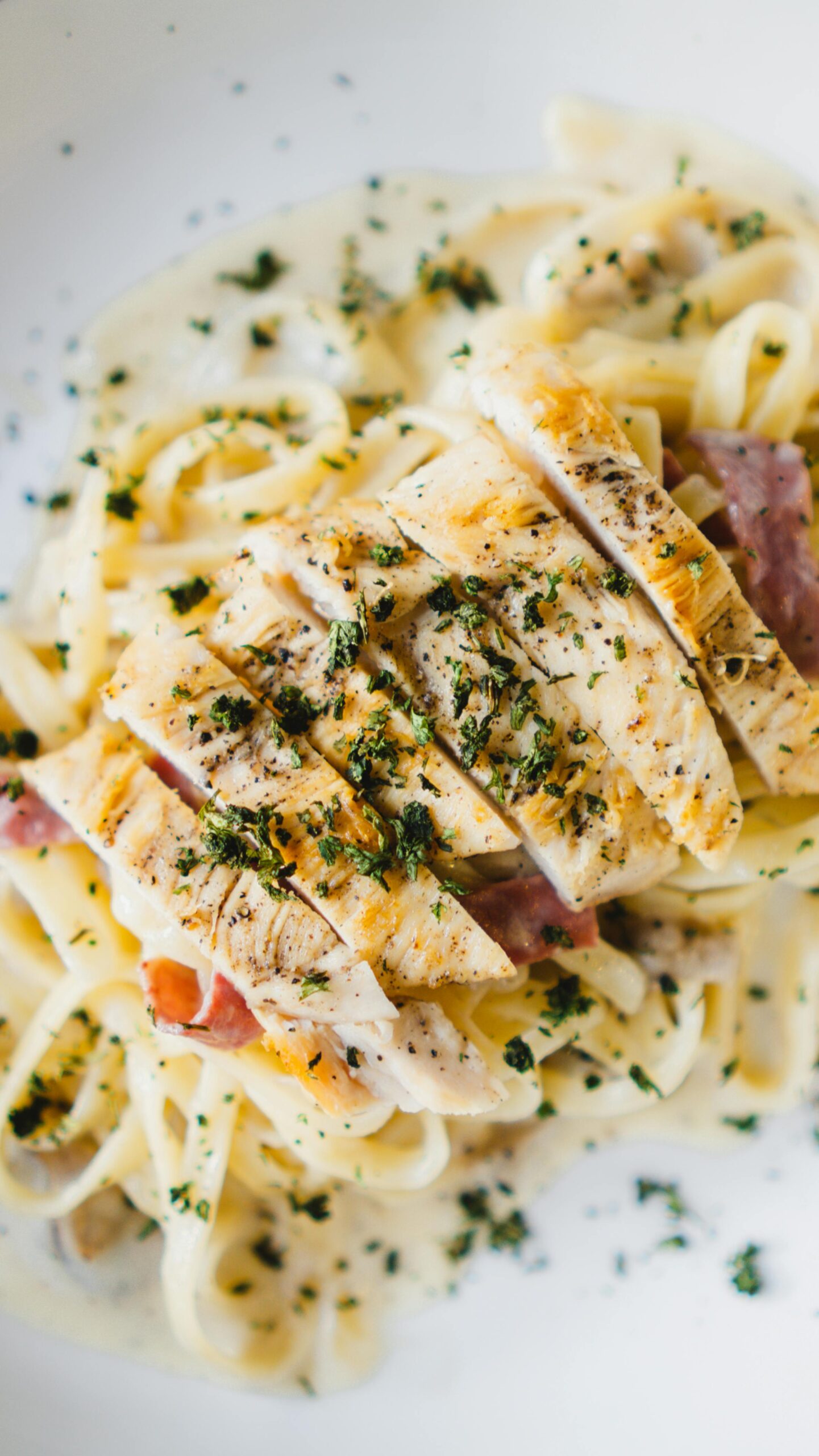 Savor a close-up of creamy chicken fettuccine pasta garnished with parsley — a delicious classic among popular Italian foods, often featured at top Italian restaurants, perfect for lunch or dinner.