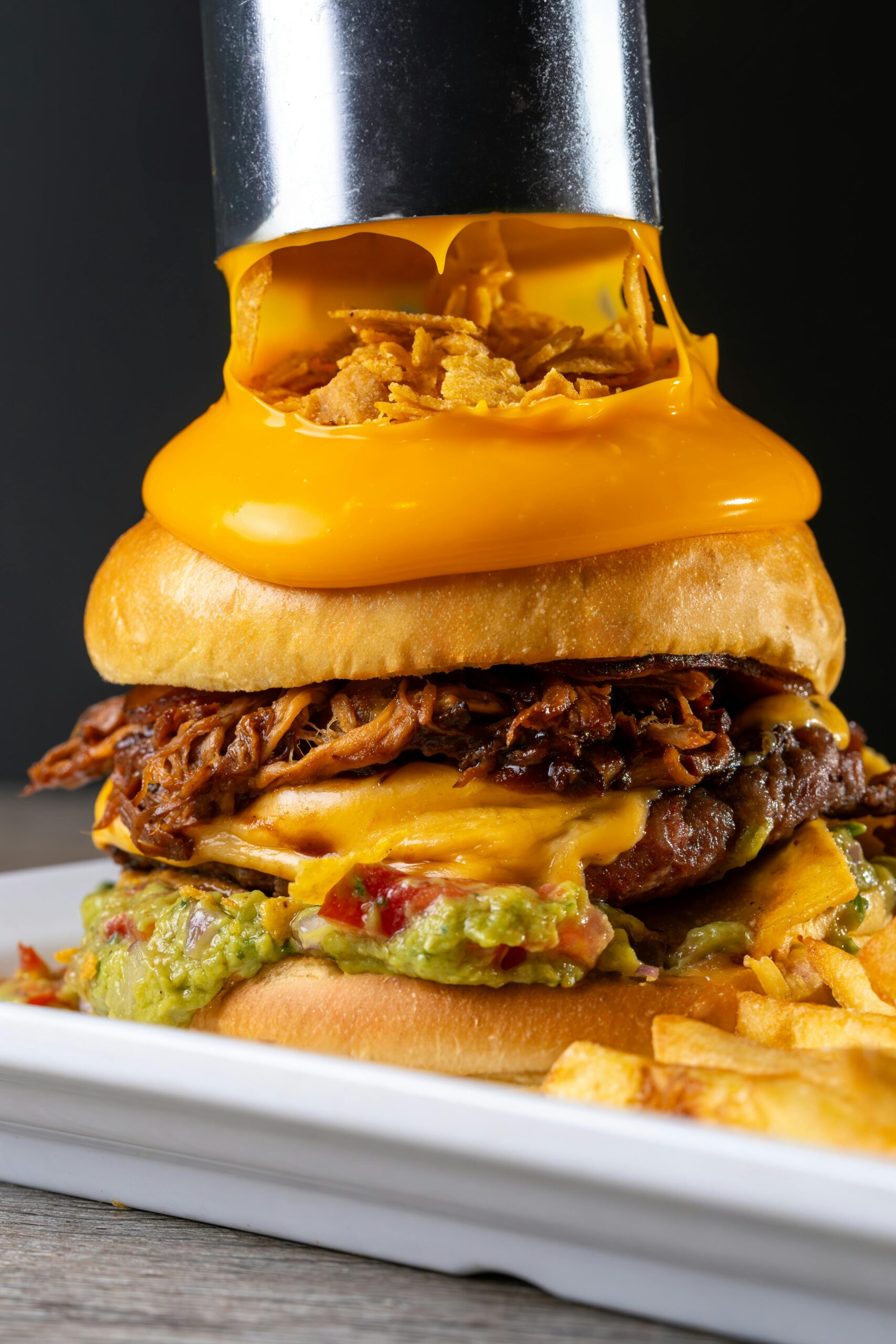 Close-up of a gourmet burger loaded with melting cheese, savory beef, and creamy guacamole — a bold twist you wouldn’t expect at traditional Italian restaurants, but one you’ll crave again and again.