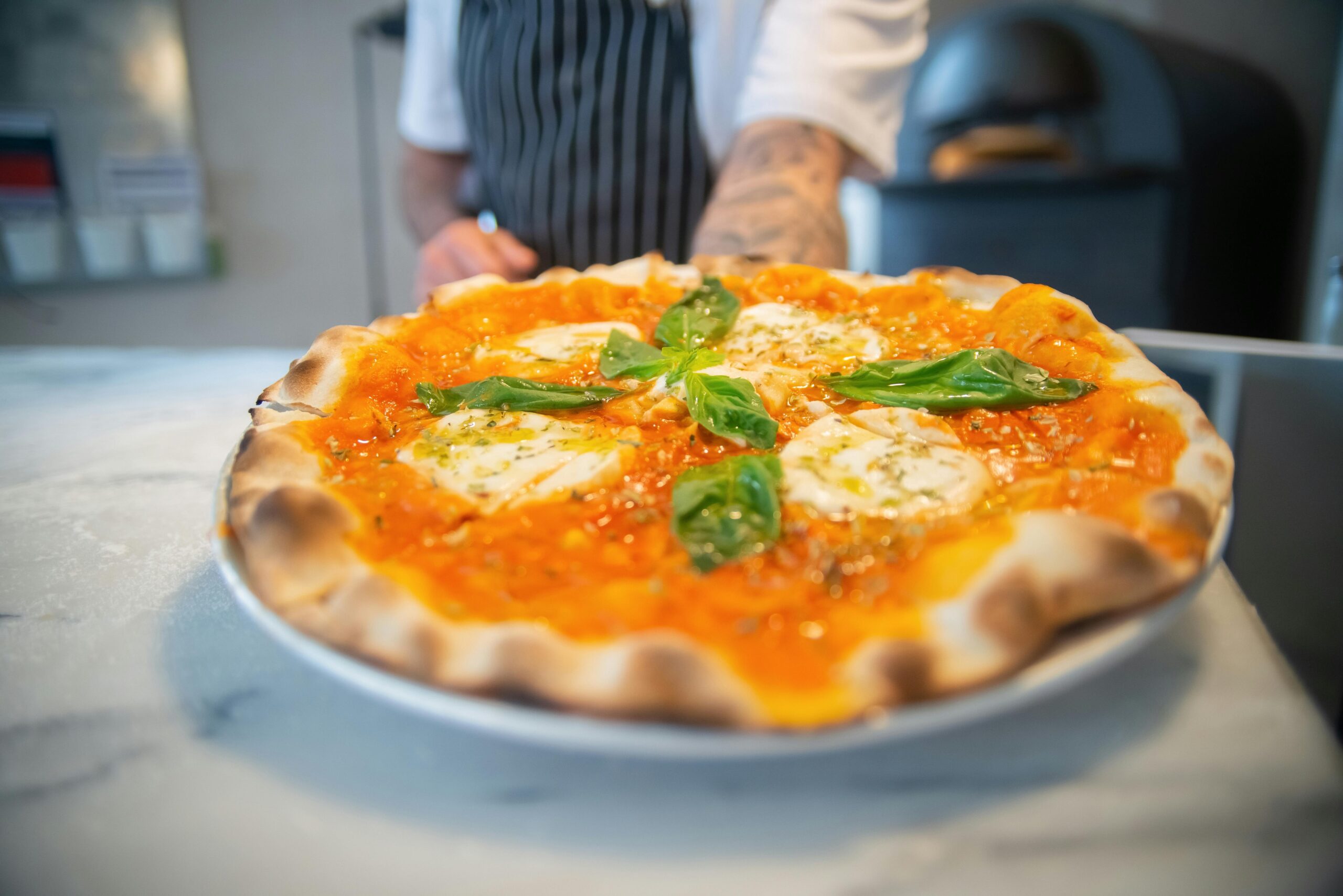 Close-up of a freshly baked Margherita pizza topped with basil, served on a marble countertop — a classic favorite found in the best Italian restaurants.