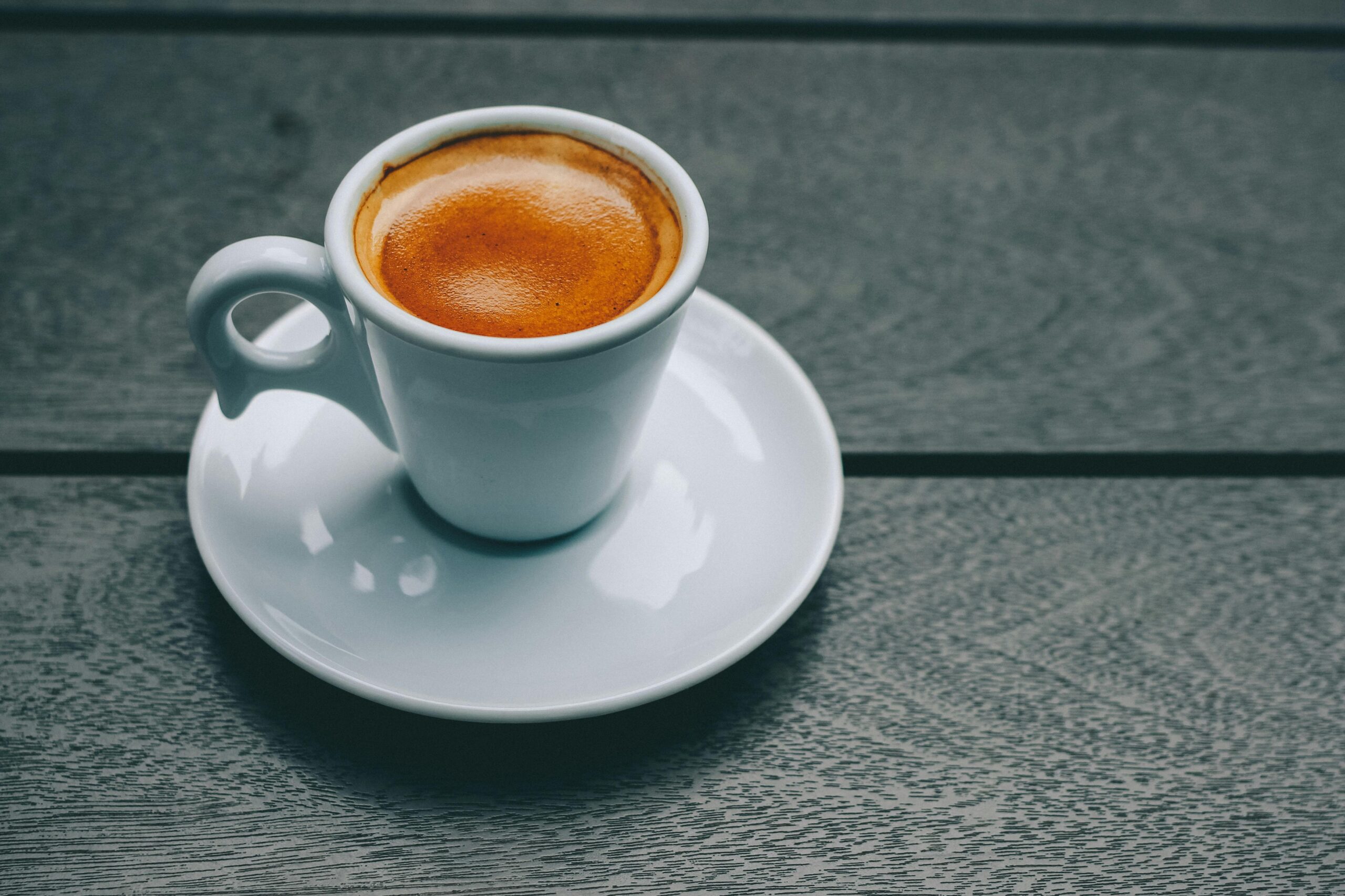 A stylish espresso served in a porcelain cup on a rustic wooden table — a classic moment coffee lovers will recognize from the best Italian restaurants.